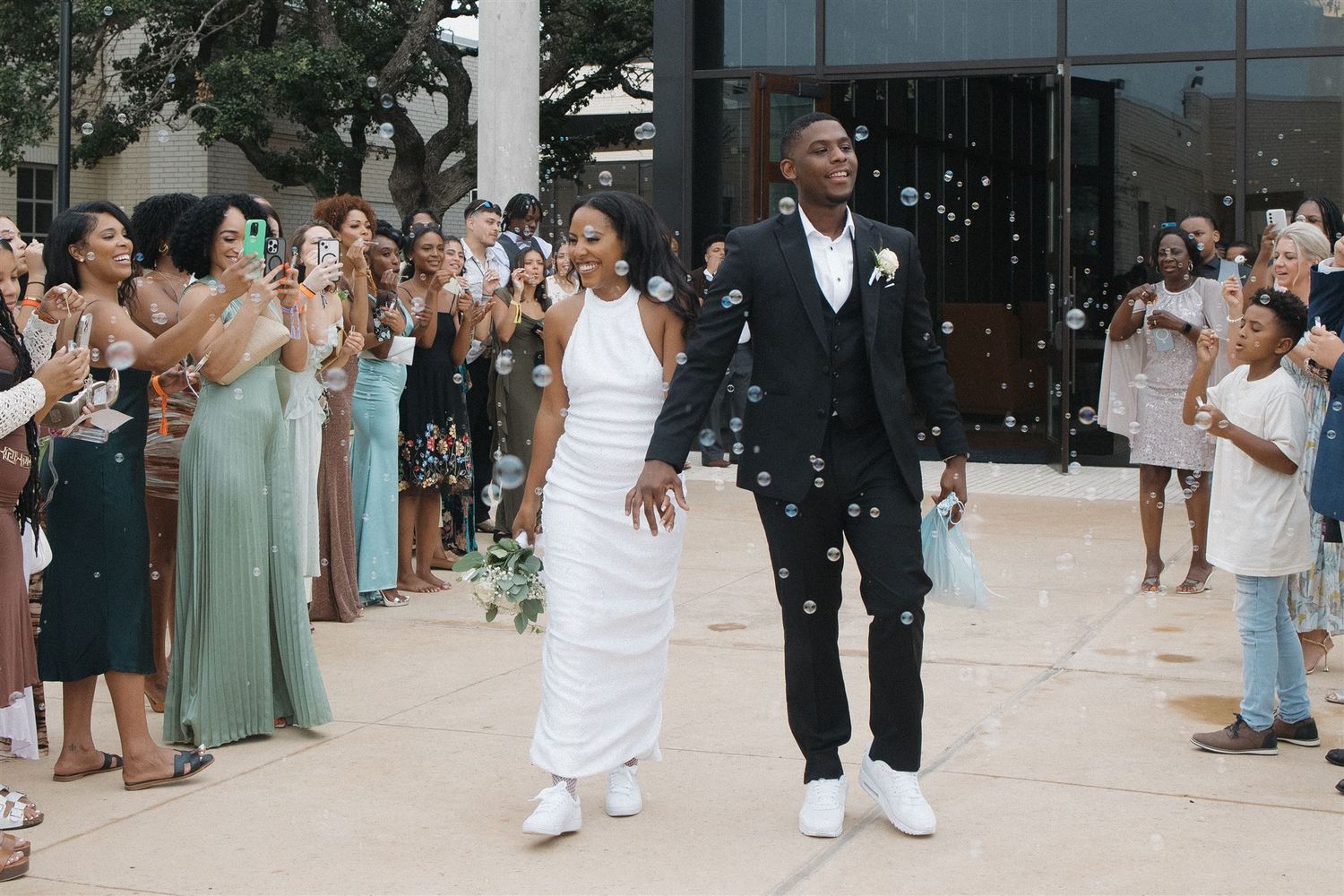 A newly married couple exits their grand wedding exit surrounded by joyful guests throwing confetti in celebration.