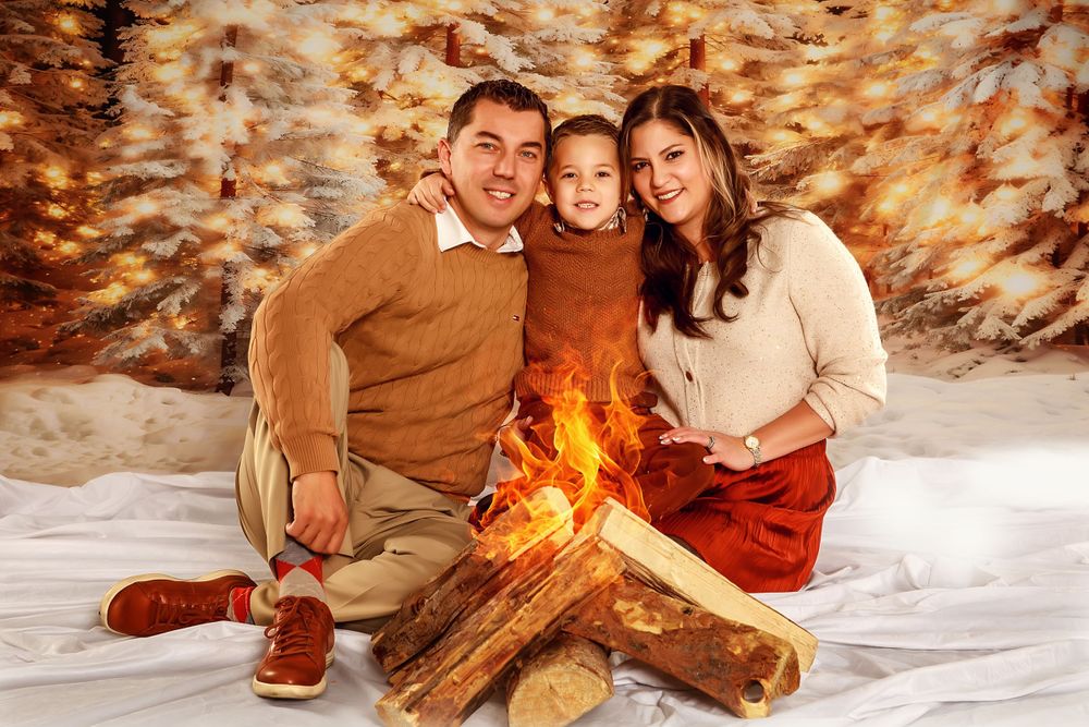 Family sits together by campfire scene in winter studio setting.