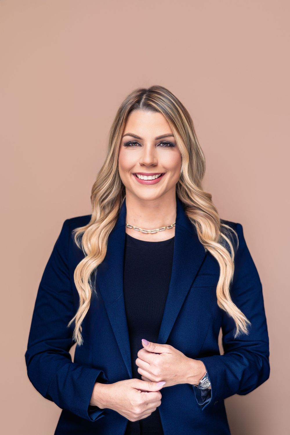 Professional headshots show person in navy blazer and black top against neutral background with warm lighting.