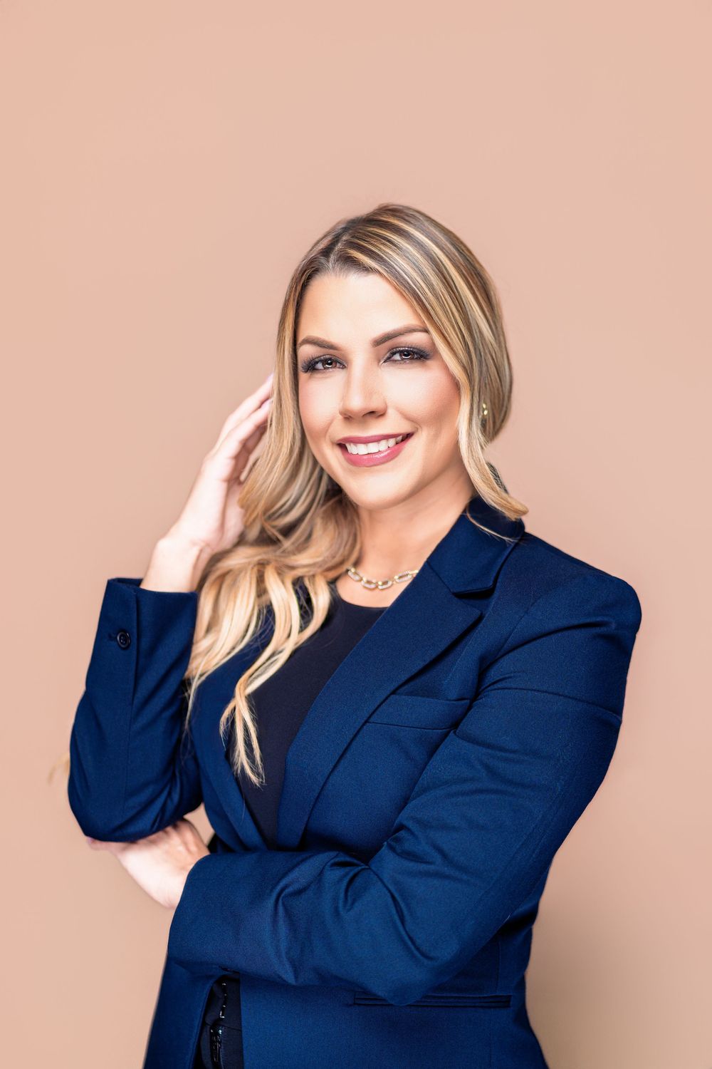 Professional portrait series showing a person in a navy blazer against a peach background with various poses and expressions.