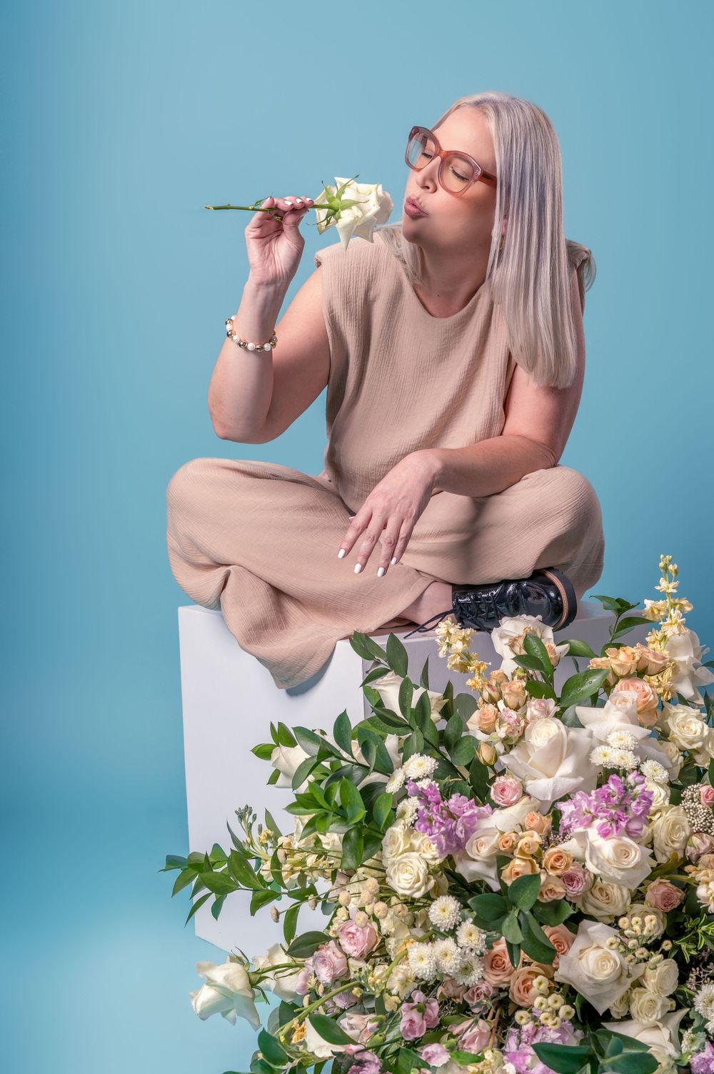 Professional photo series of someone posing with elegant floral arrangements against a blue backdrop.
