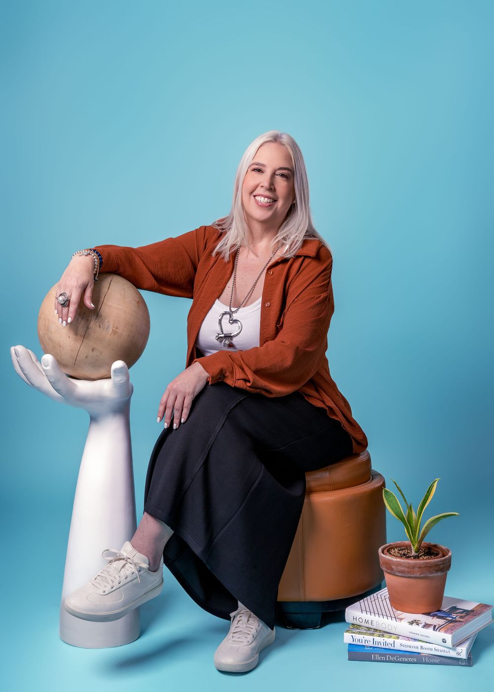 Casual portrait series showing someone in rust-colored blazer and black dress with potted plants.