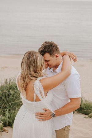 An intimate moment shared between a couple on a beach with the ocean horizon behind them.