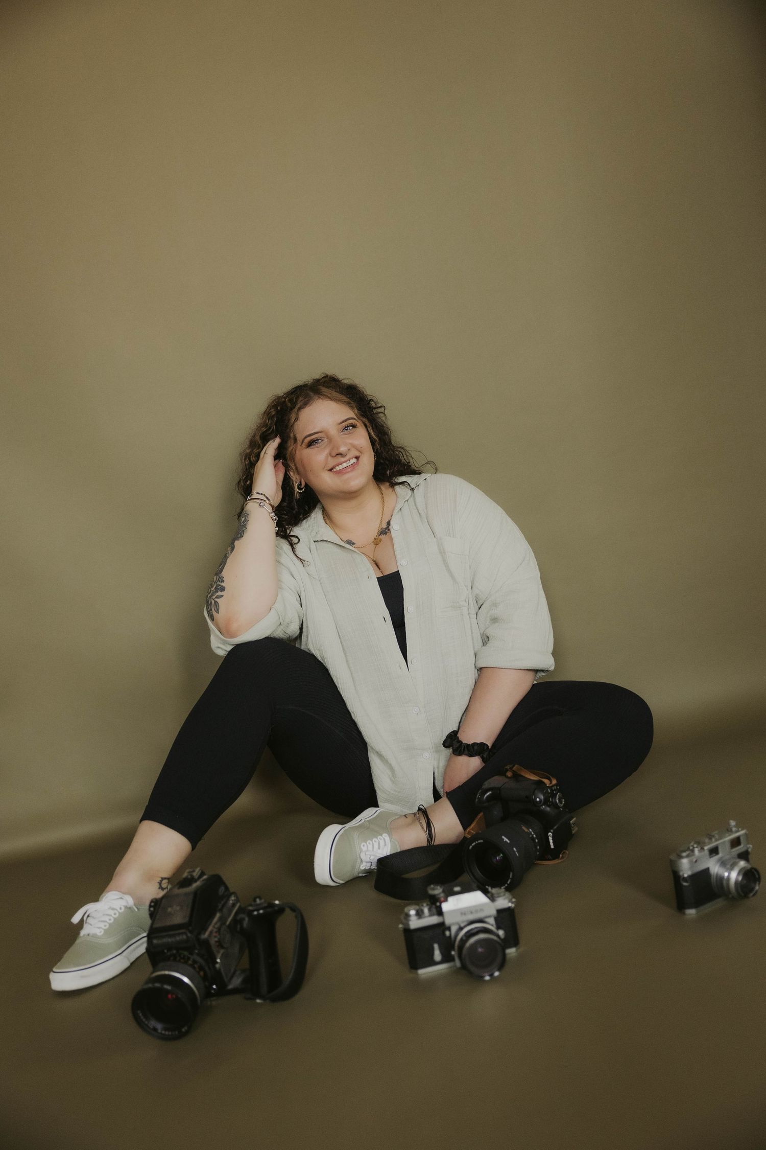 Creative portrait session with vintage cameras against neutral backdrop.