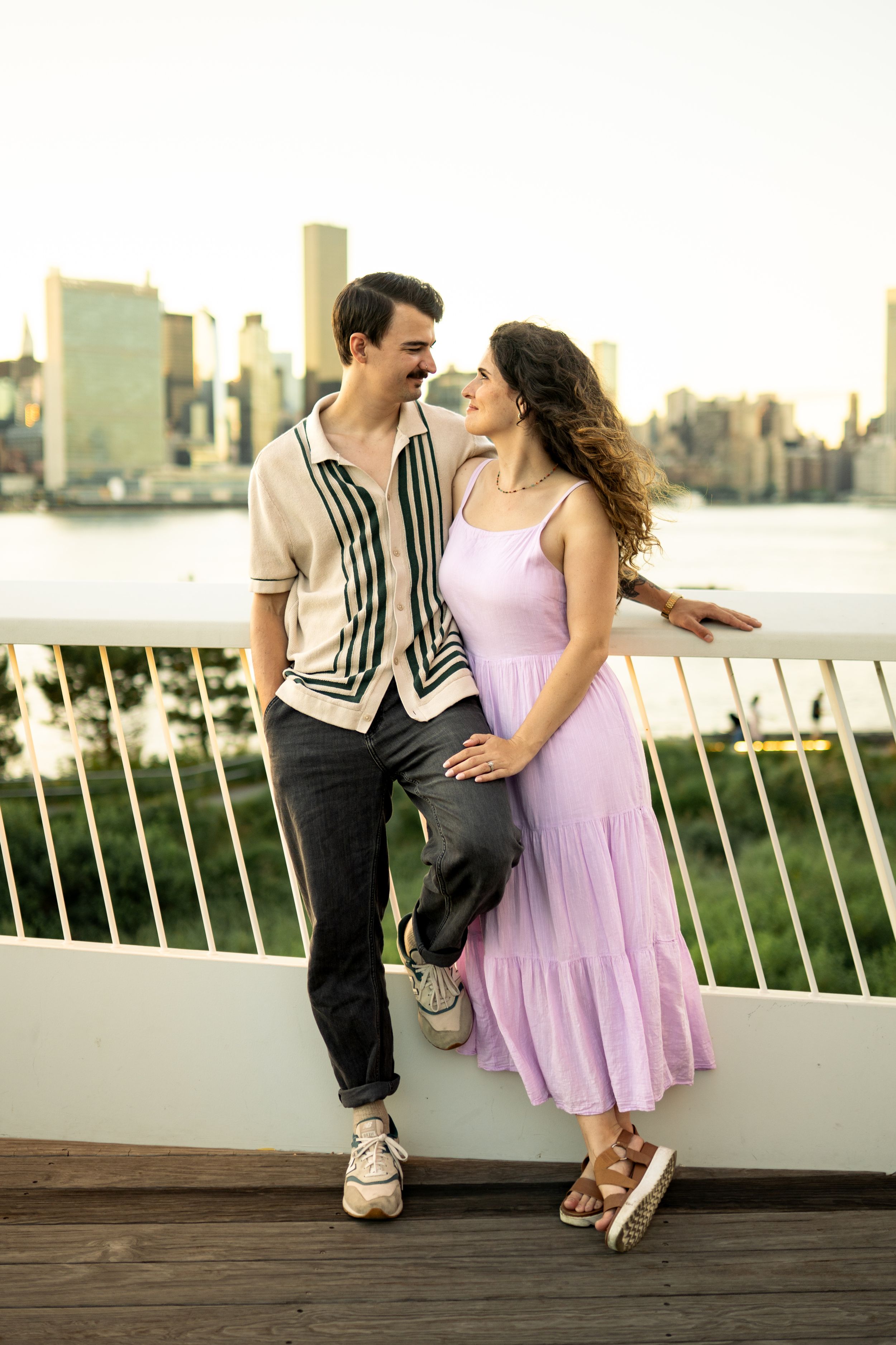 Romantic couple in vintage style clothing pose playfully against city skyline.