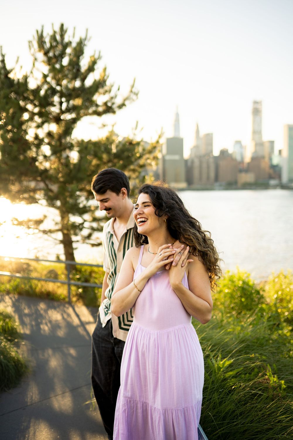 Two people share a joyful moment together with a city skyline and sunset in the background.