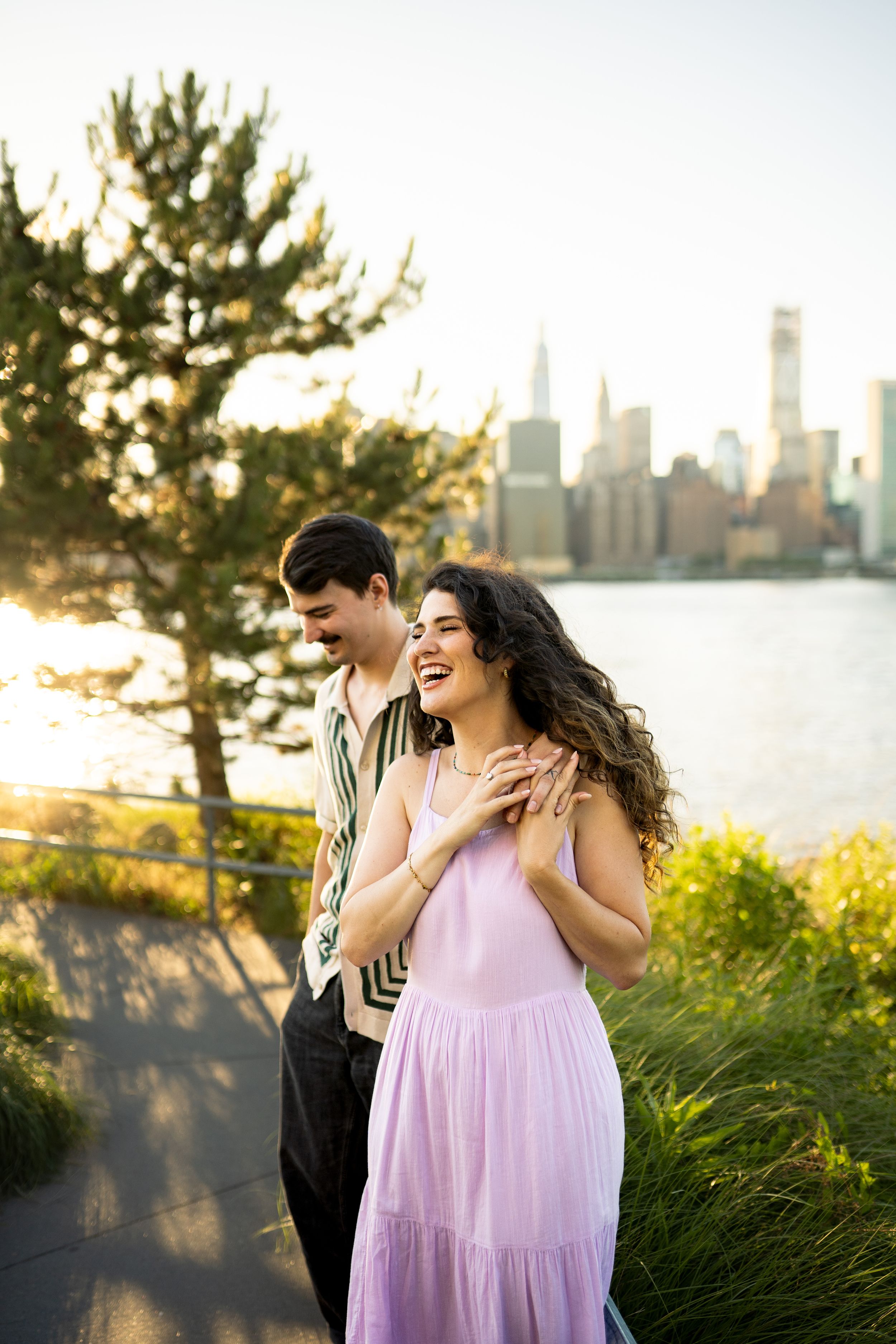Two people share a joyful moment together with a city skyline and sunset in the background.