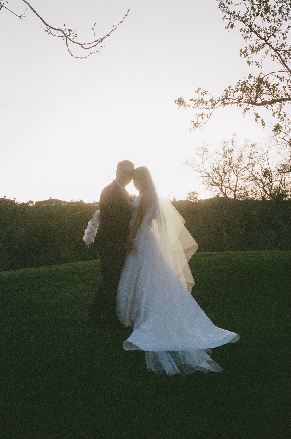 Romantic sunset wedding portrait with couple embracing in a garden setting.