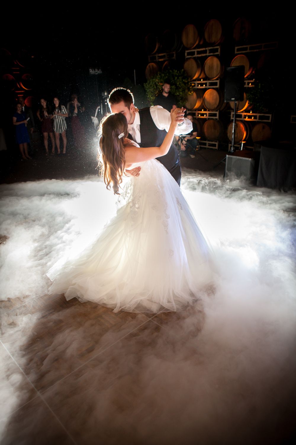 A romantic first dance captured with dramatic fog effects on a dark dance floor.