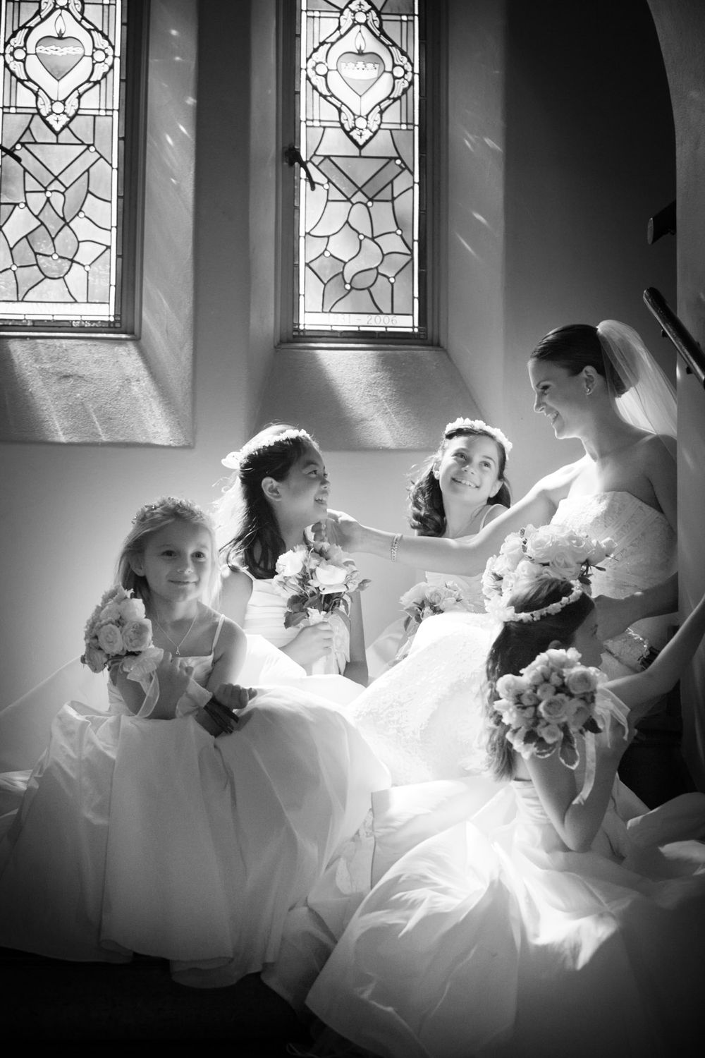 Artistic black and white bridal party photos with dramatic window lighting in a church.