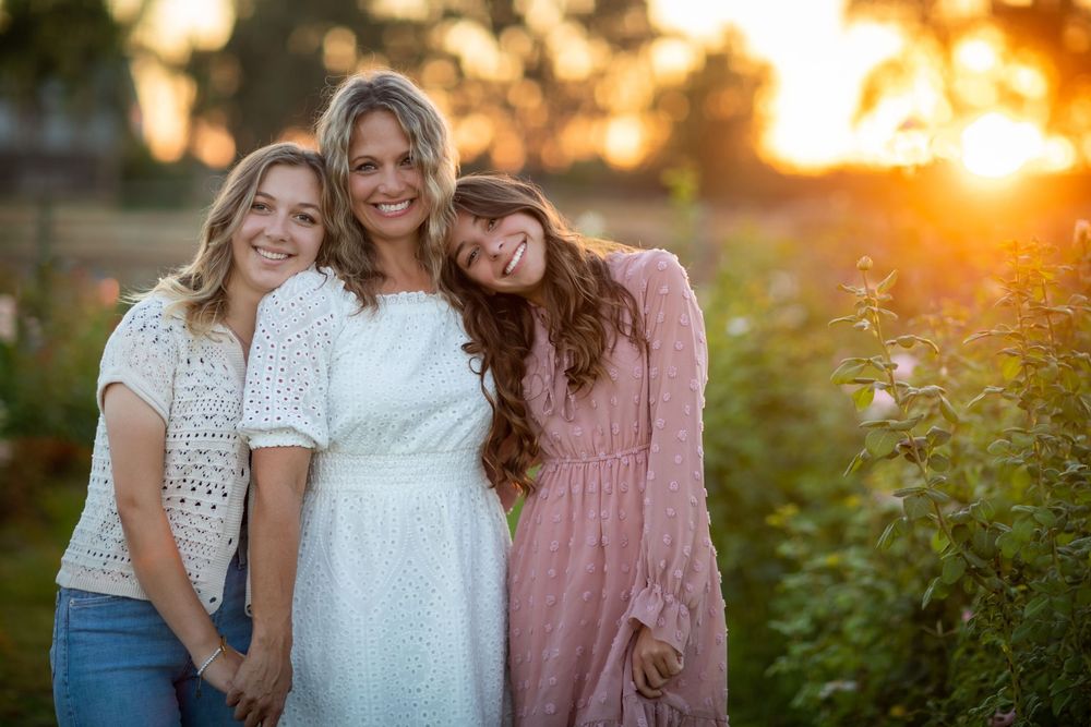 A group poses together outdoors during golden hour sunset with warm glowing light in the background.
