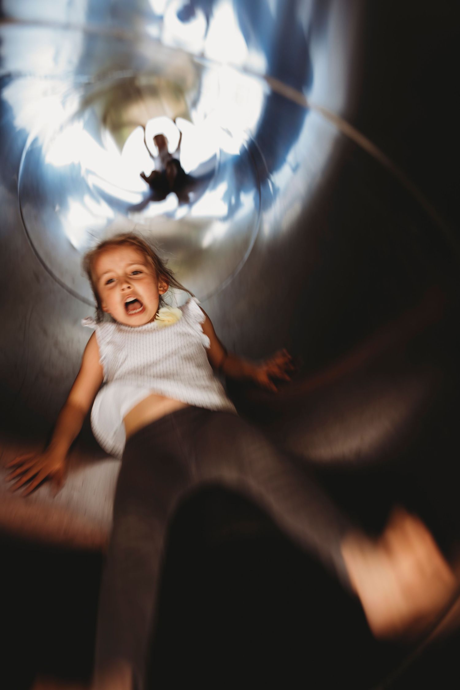 Creative shadow play photo captured through a tunnel slide at a playground.