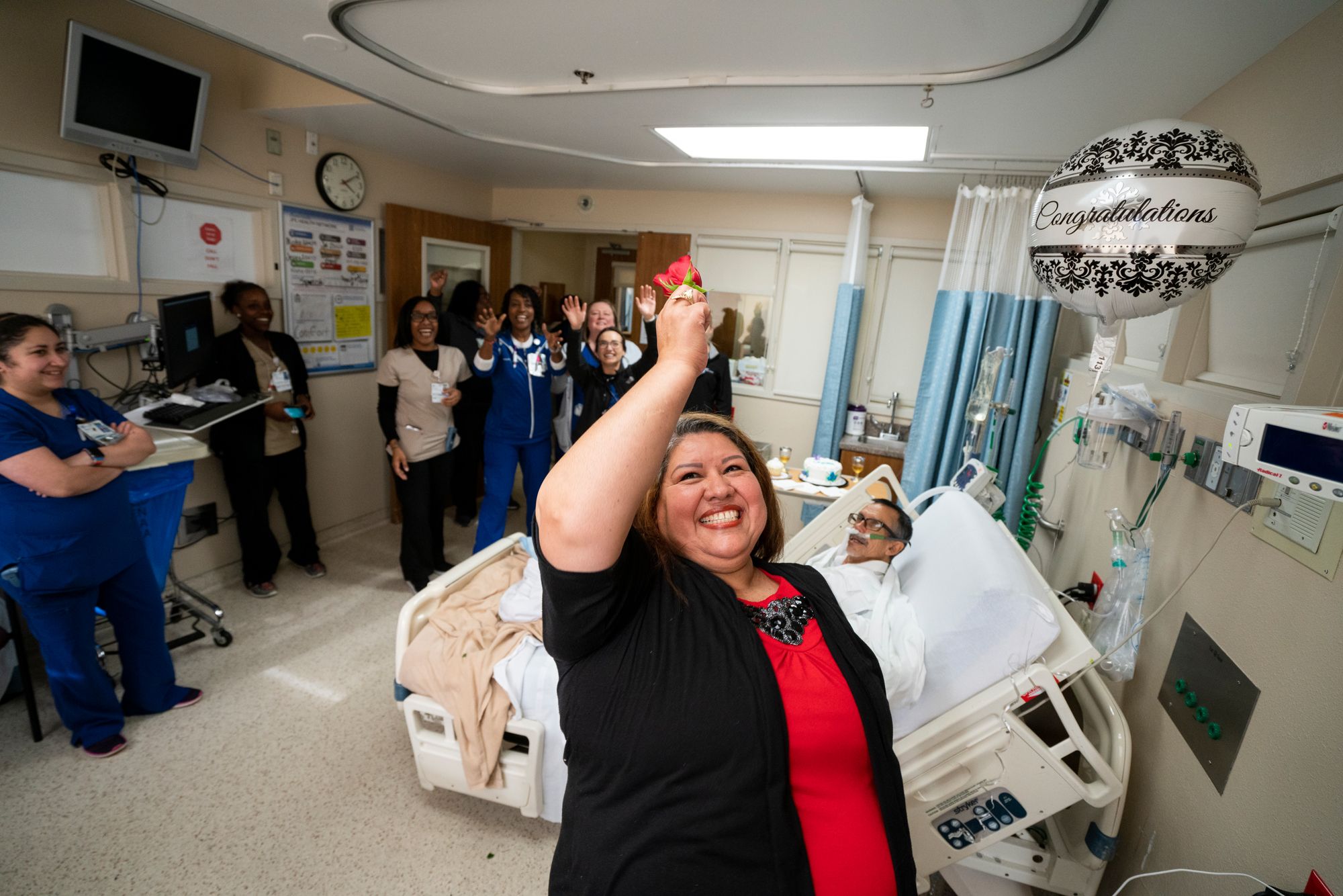 Hospital nurses celebrate with patient and family during wedding ceremony in hospital bed.