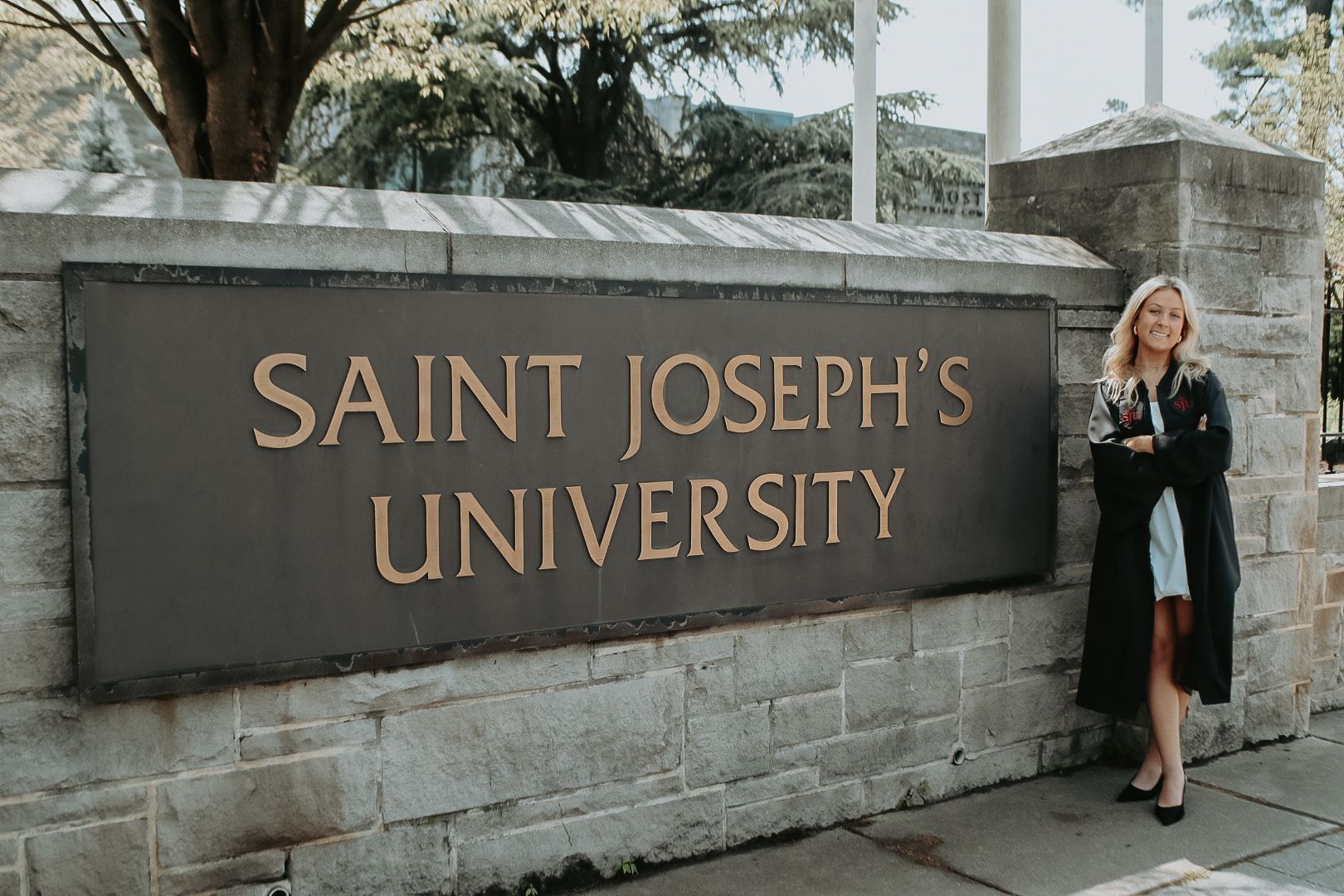 Stone entrance sign and wall for Saint Joseph's University campus on a sunny day.