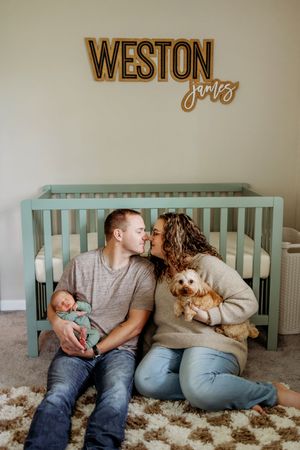 Couple relaxing together on floor near mint green furniture with name 'WESTON' on wall.