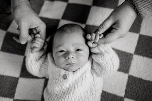 Black and white portrait of newborn baby on checkered background.