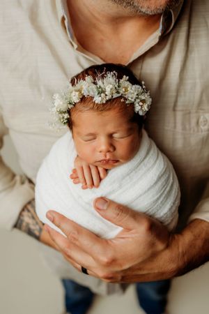 Gentle newborn portrait with delicate flower crown and white wrap.