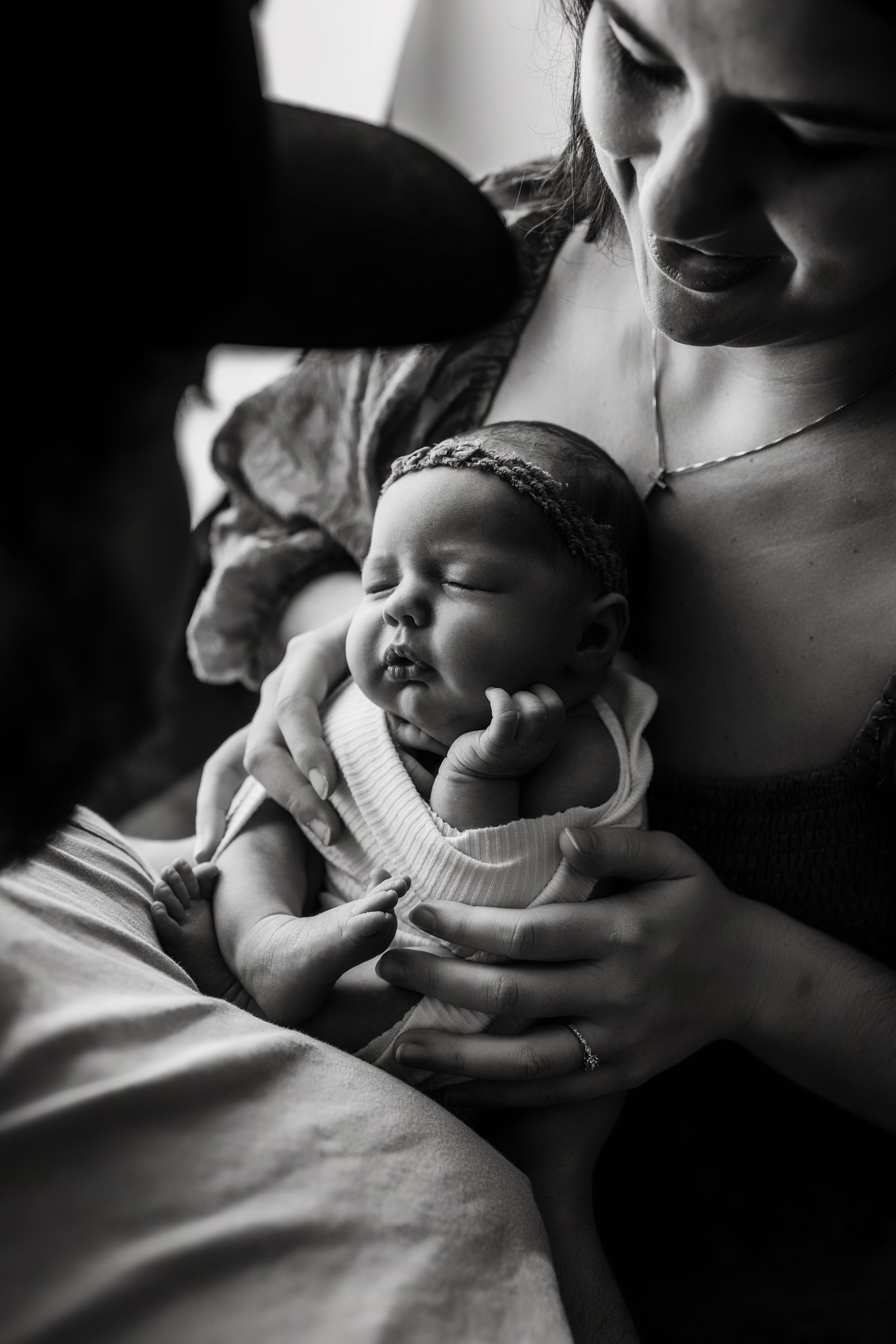 Black and white photo series showing tender moments between parent and infant in soft natural light.
