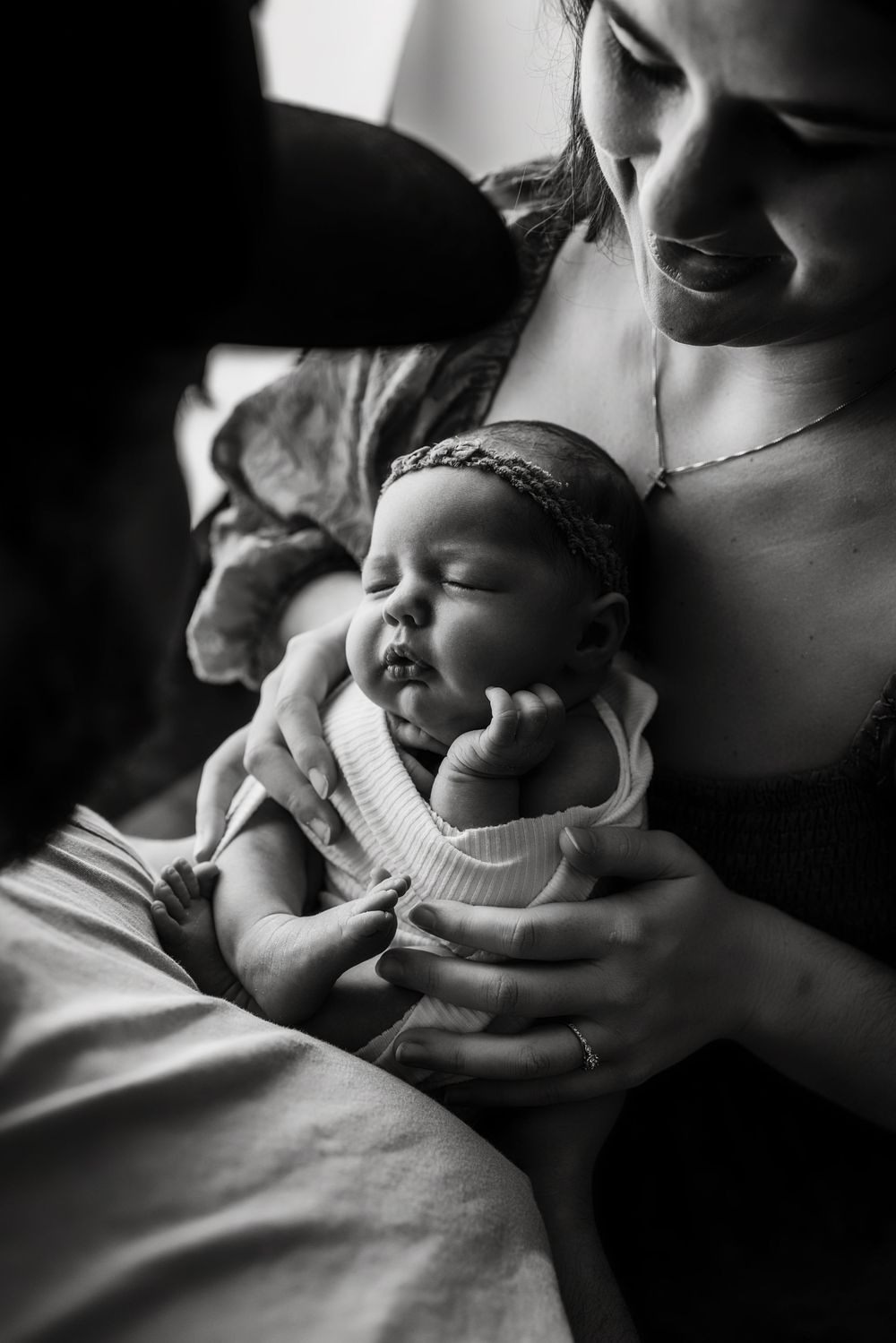 Black and white photo series showing tender moments between parent and infant in soft natural light.