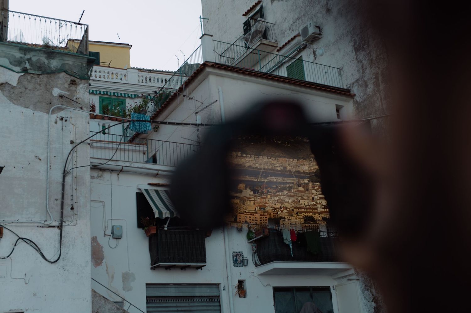 Urban architecture viewed through circular frame with textured walls and hanging laundry.
