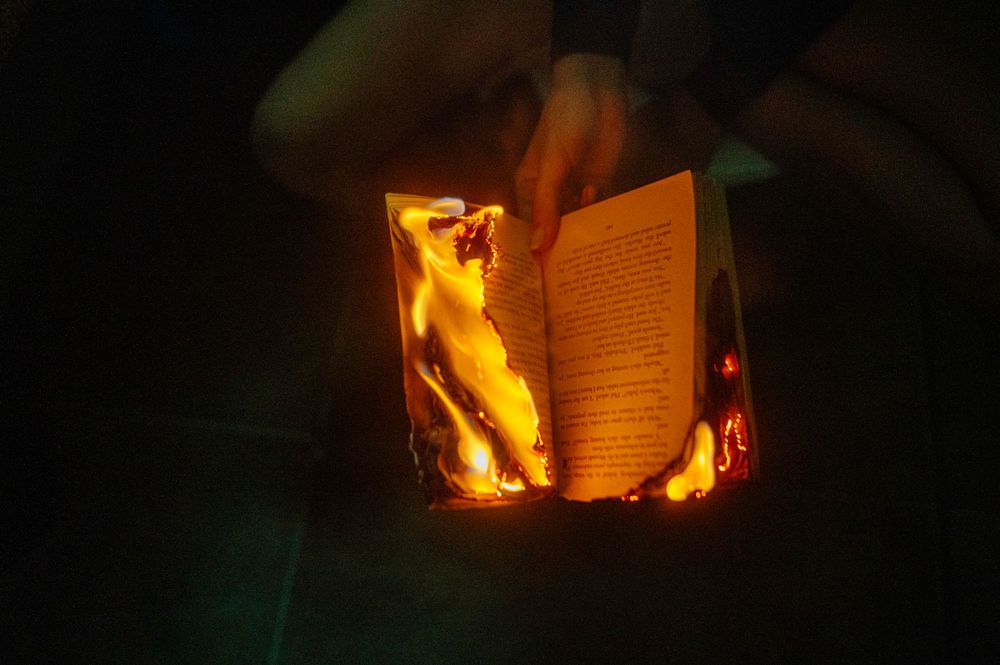 A burning book with pages illuminated by flames creating a dramatic atmospheric effect.