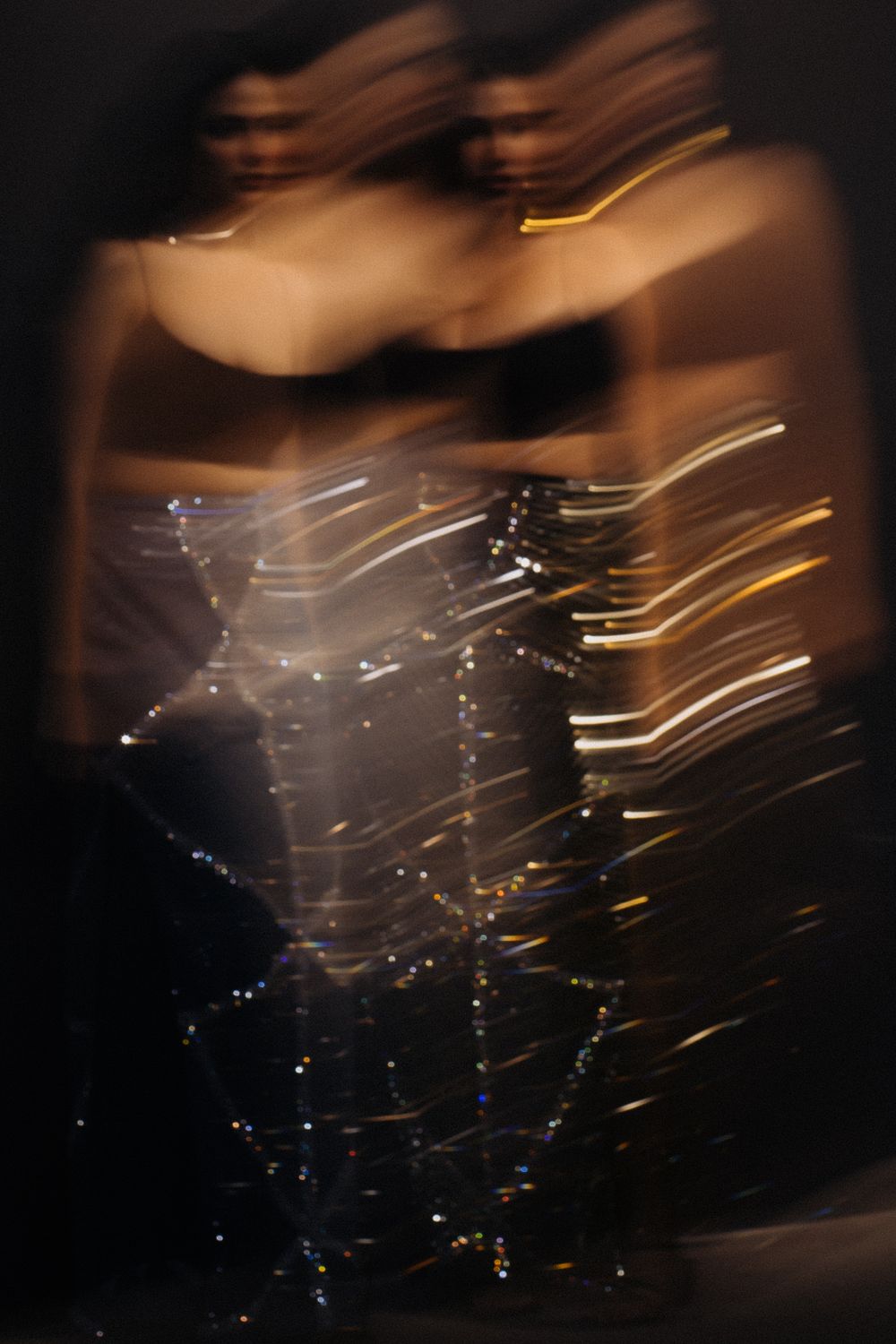 Abstract long exposure photograph with light trails creating motion blur effect against dark background.