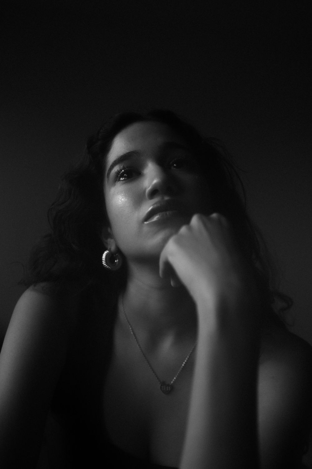 Dramatic black and white portrait with jewelry and moody lighting creating an artistic composition.