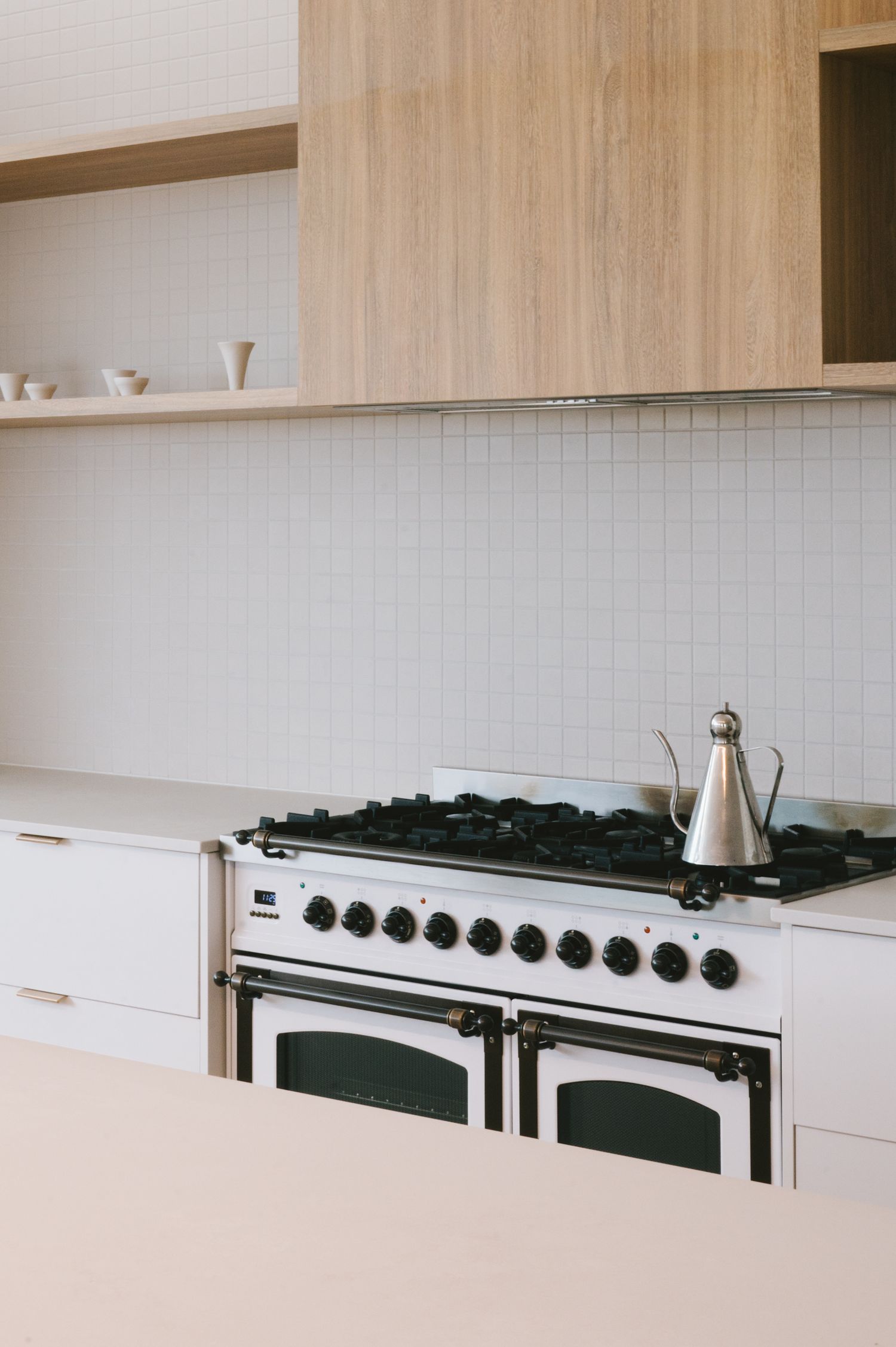 Vintage-style gas range stove with white tile backsplash and wooden upper cabinets.