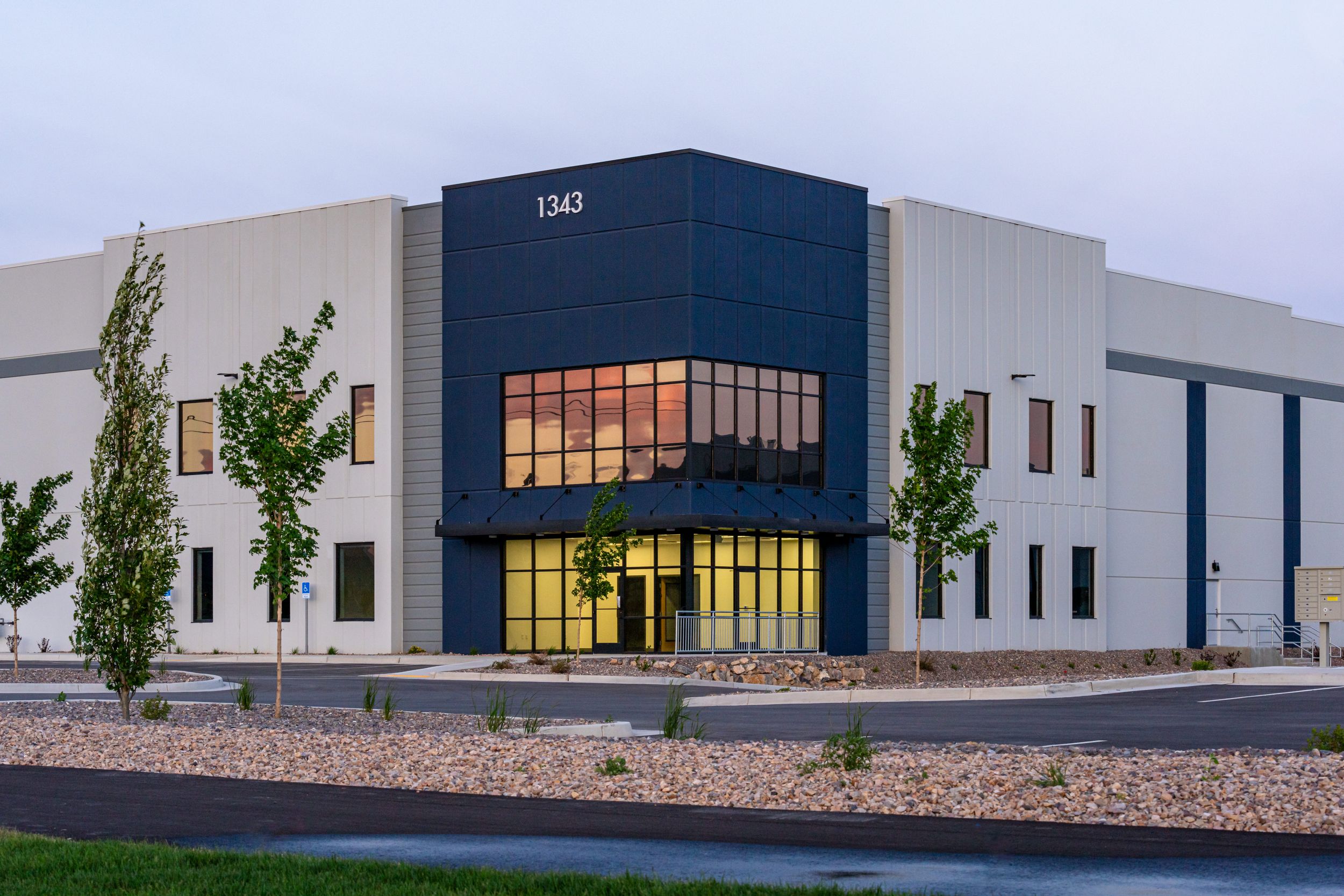 A modern commercial building with a mix of white and navy blue exterior panels. Large windows on the front.
