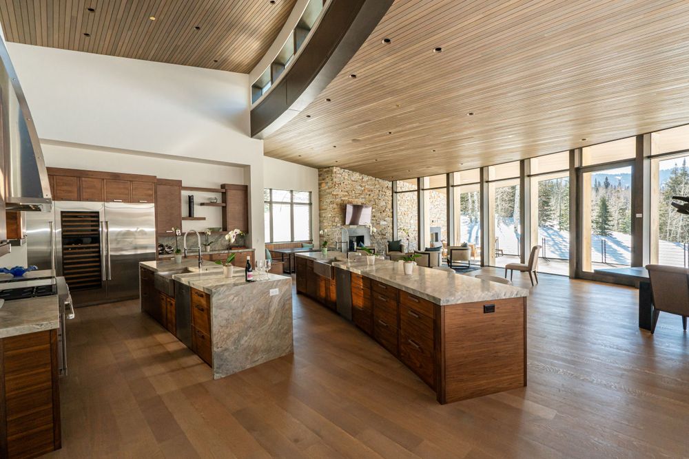 Spacious modern kitchen and living area with wooden ceiling and floors, large windows.