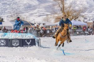 A skier being pulled by a rider on horseback across a snowy course during a skijoring event.