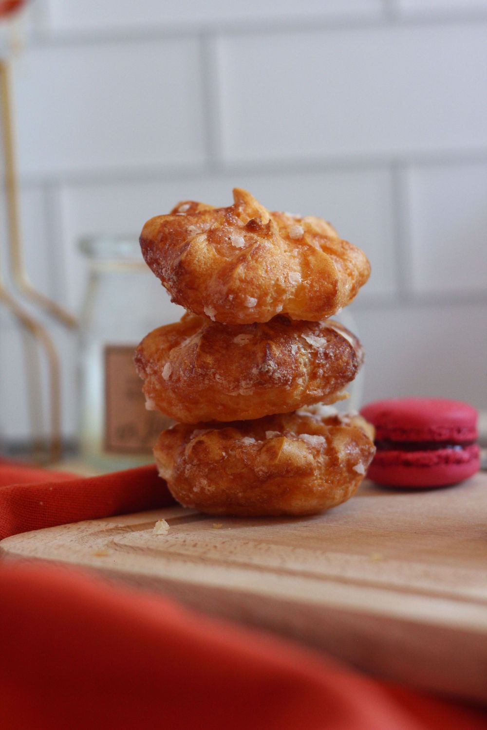 Close-up shots of golden pastries with red macarons on a wooden cutting board.