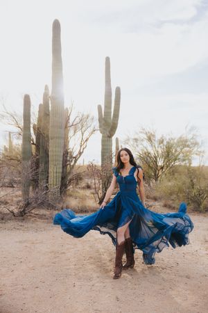 A flowing cobalt dress catches the wind during a desert photoshoot with saguaro cacti.
