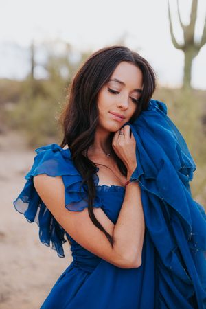 Close-up shots showcase the details of a ruffled royal blue dress in desert lighting.