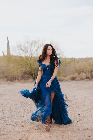 Dynamic movements in a navy blue dress create elegant shapes against desert sand.