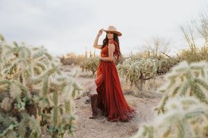 Ethereal desert photoshoot featuring a billowing red dress among scattered cacti.