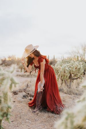 A dramatic red dress flows in the desert breeze surrounded by desert flora.