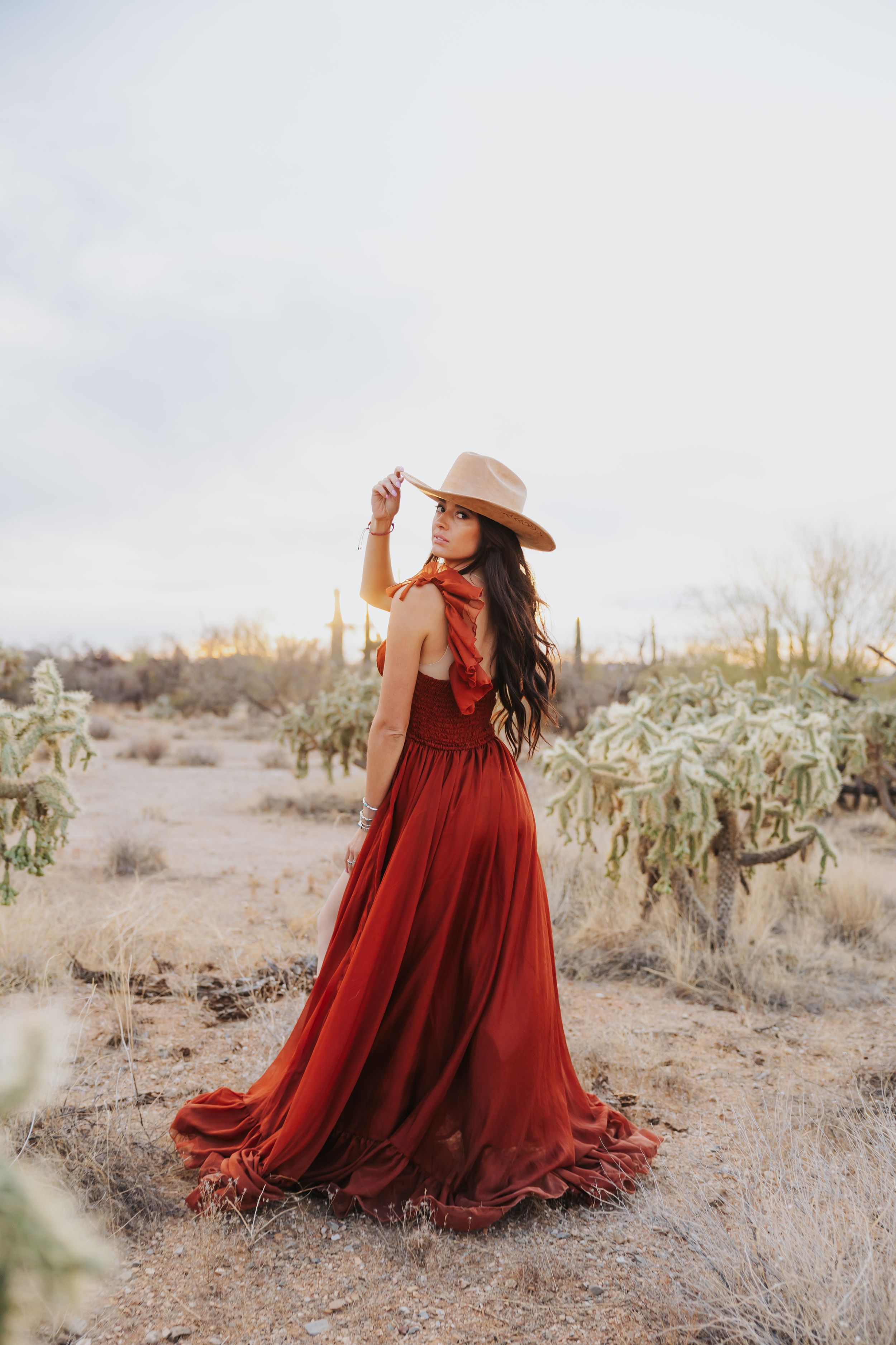 A flowing crimson dress creates movement against a desert backdrop with cacti.