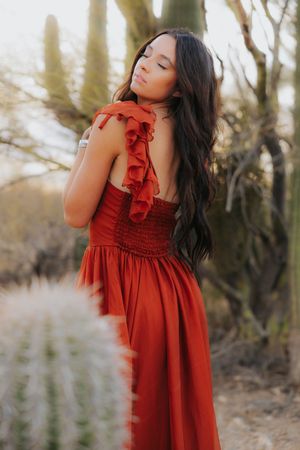 Delicate red dress with ruffled details photographed in soft desert lighting.