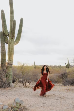 Elegant red dress movement captured among desert flora and saguaro cacti.