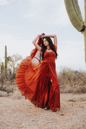 A flowing red dress creates dramatic movement against the desert landscape.