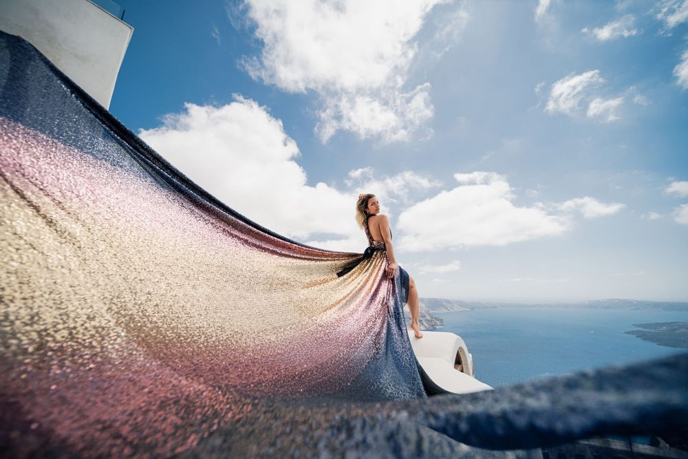 Dreamy dress fabric movement captured against Santorini's coastal landscape.