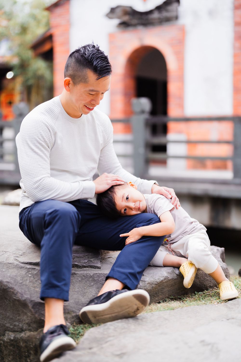 a kid laying on dad's leg on the rock at Lin An Tai Historical House and Museum