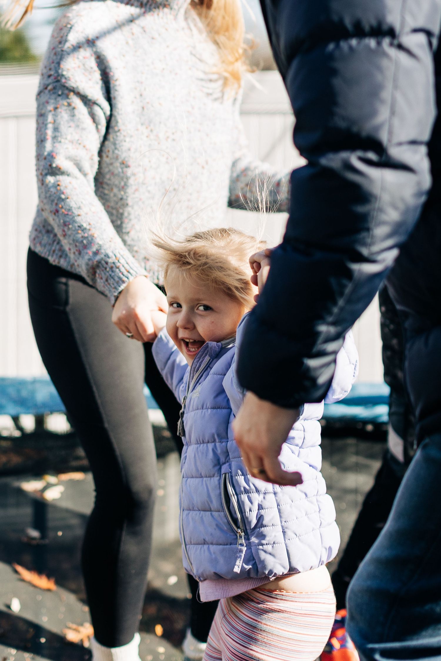 Family spending time together outdoors on autumn day wearing warm coats.