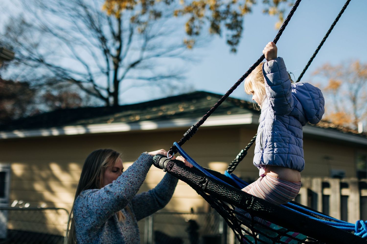 Playing on outdoor swing set in backyard during autumn afternoon.
