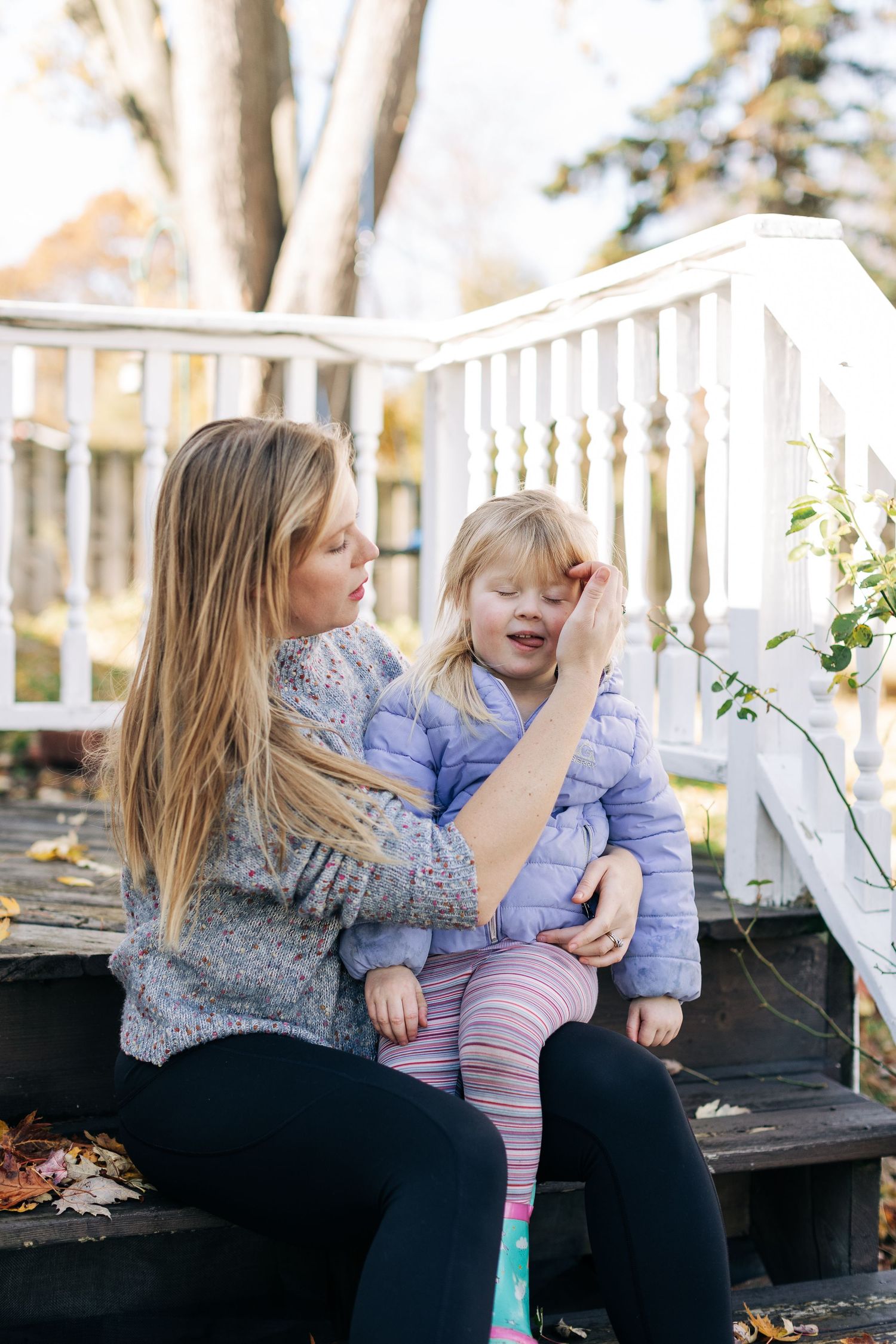 Tender moment shared on wooden porch steps surrounded by fall foliage.