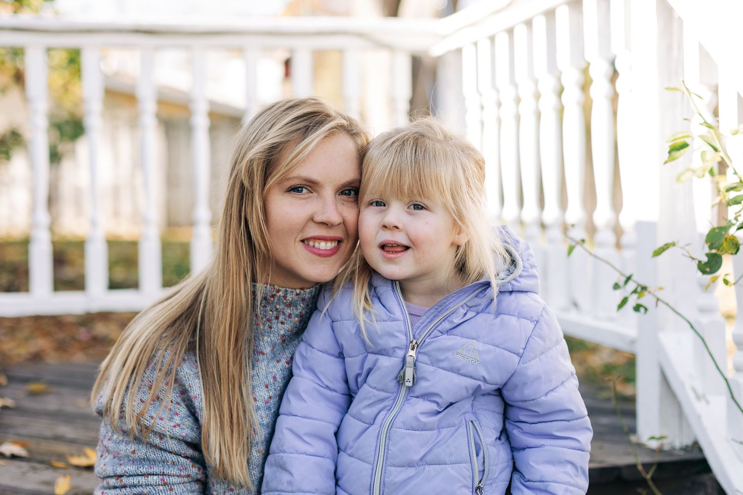 Cozy autumn portrait on white porch wearing matching gray and purple outfits.