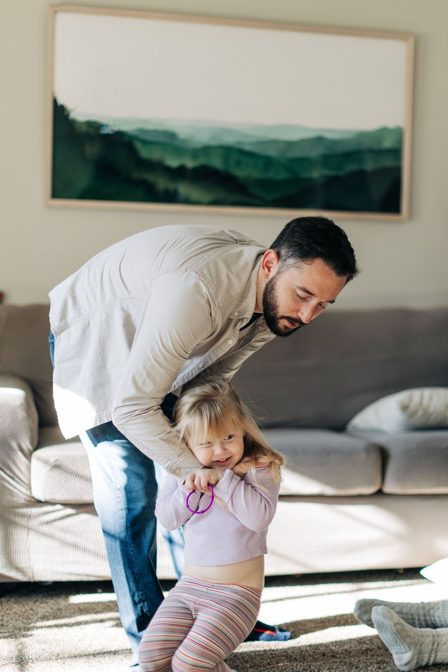 A playful moment between parent and child in a living room with modern decor.