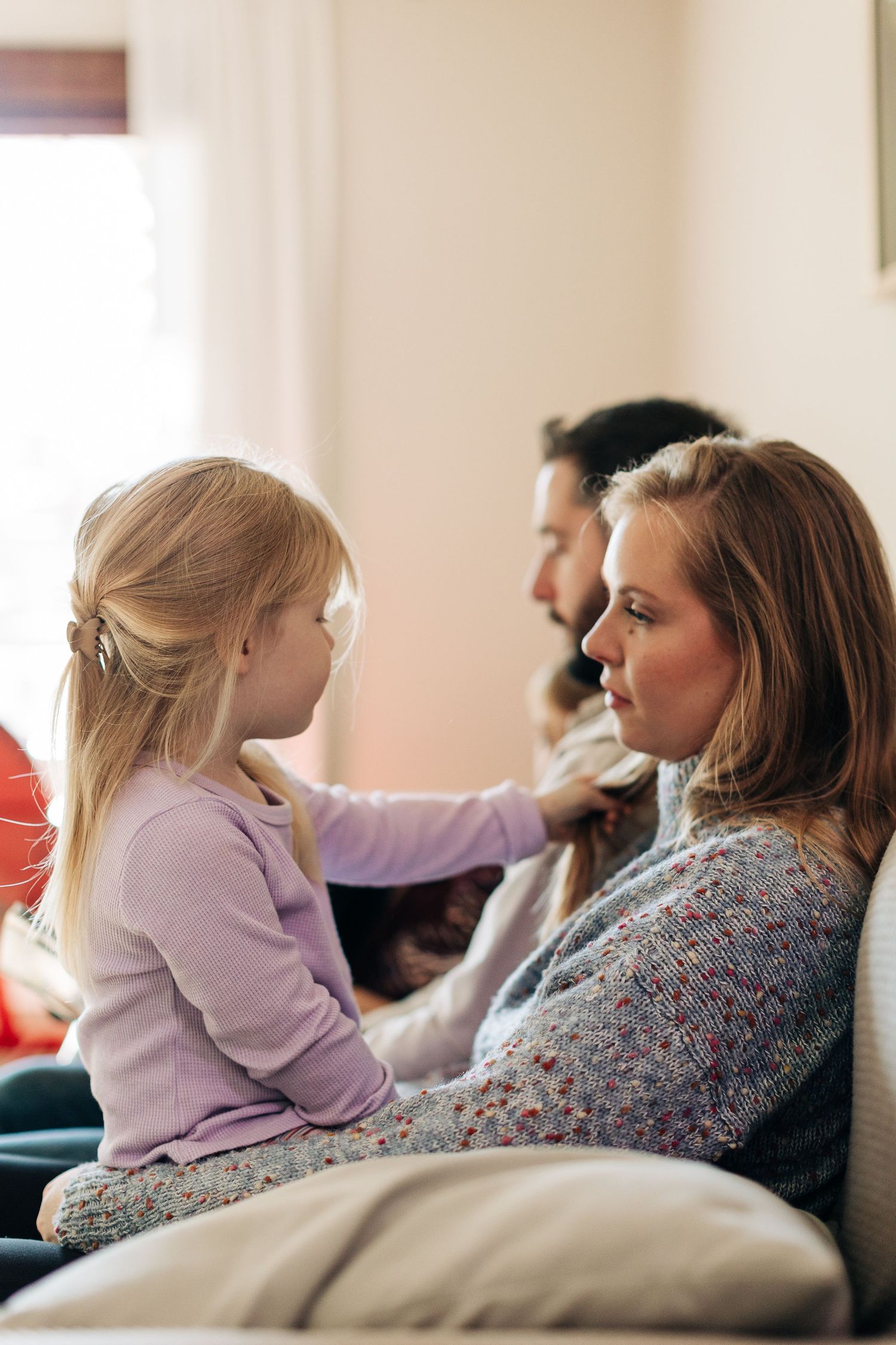 Intimate family moment shared on couch in natural light.