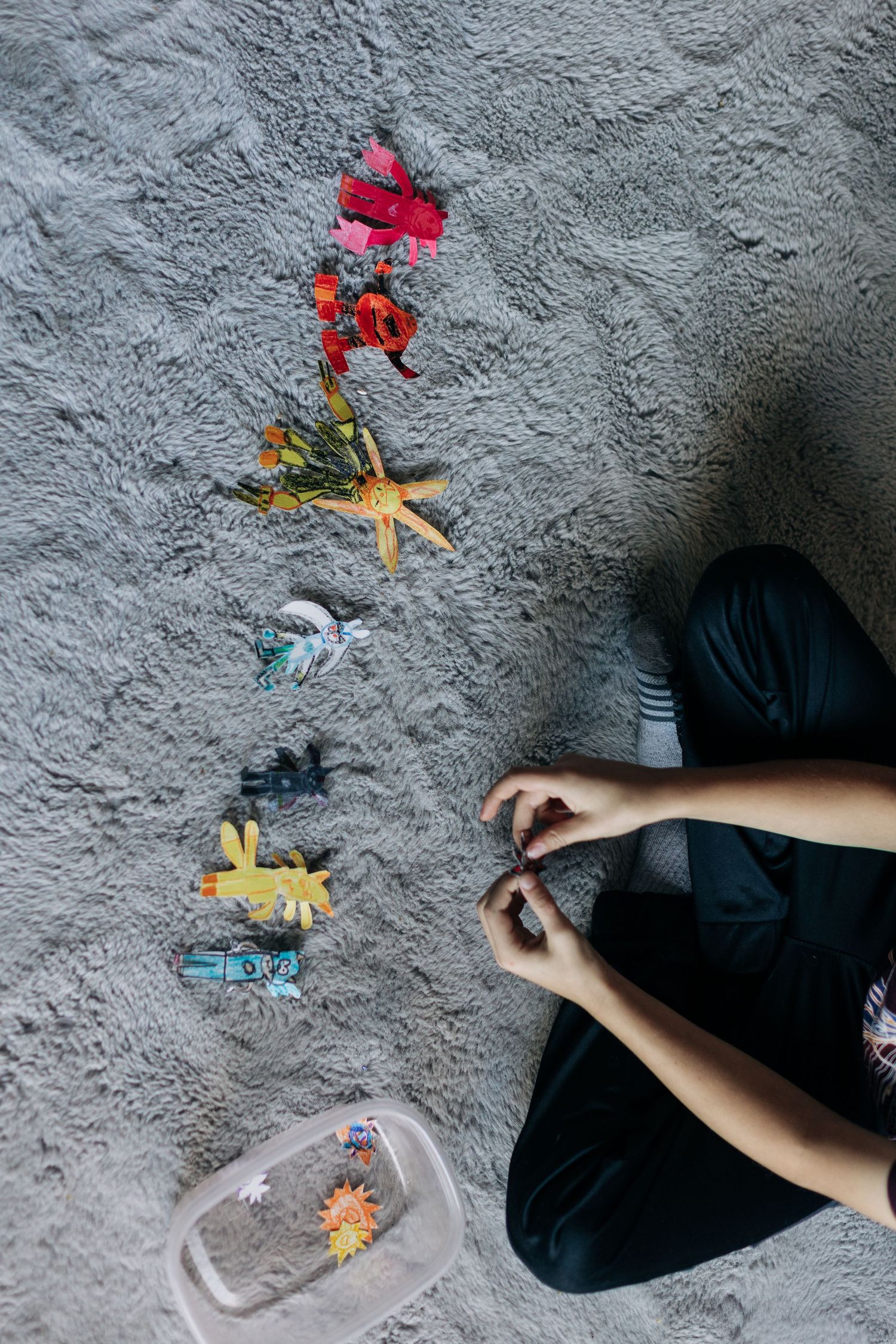 Colorful toy dinosaurs arranged in a line on gray carpet.